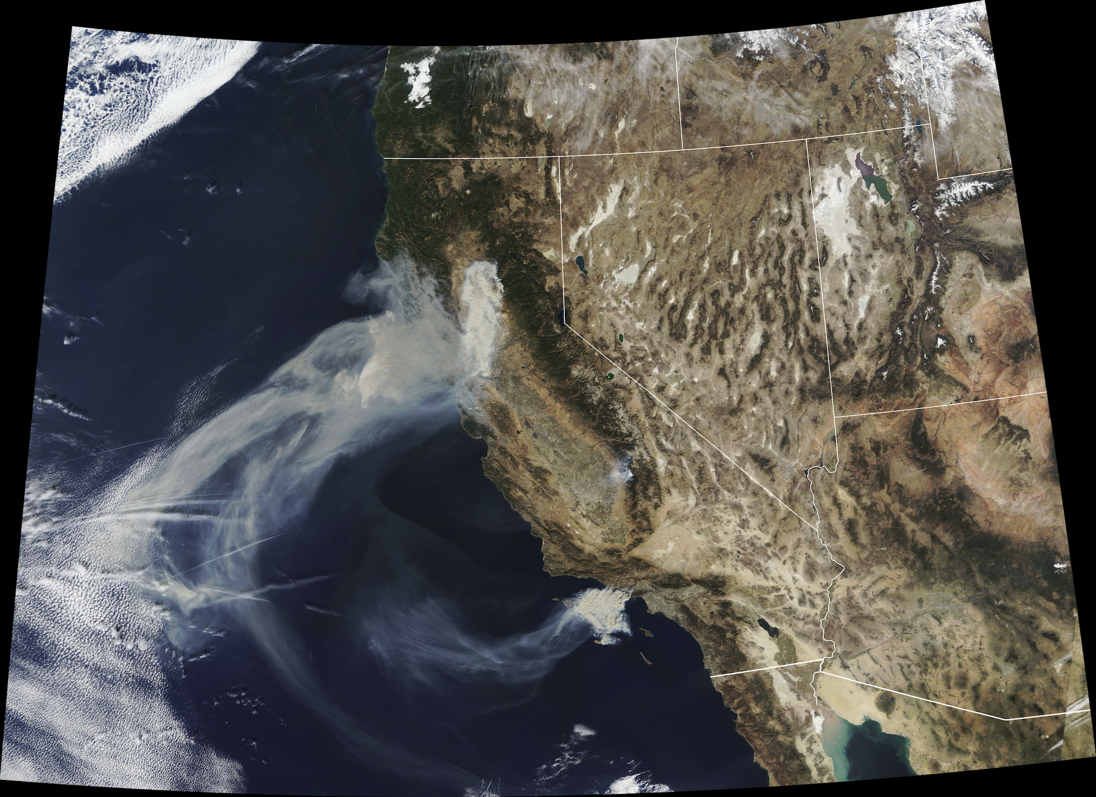 Natural-color satellite image of California showing large smoke plumes from the Camp Fire in the north and the Hill and Woolsey Fires in the south, spreading west over the Pacific